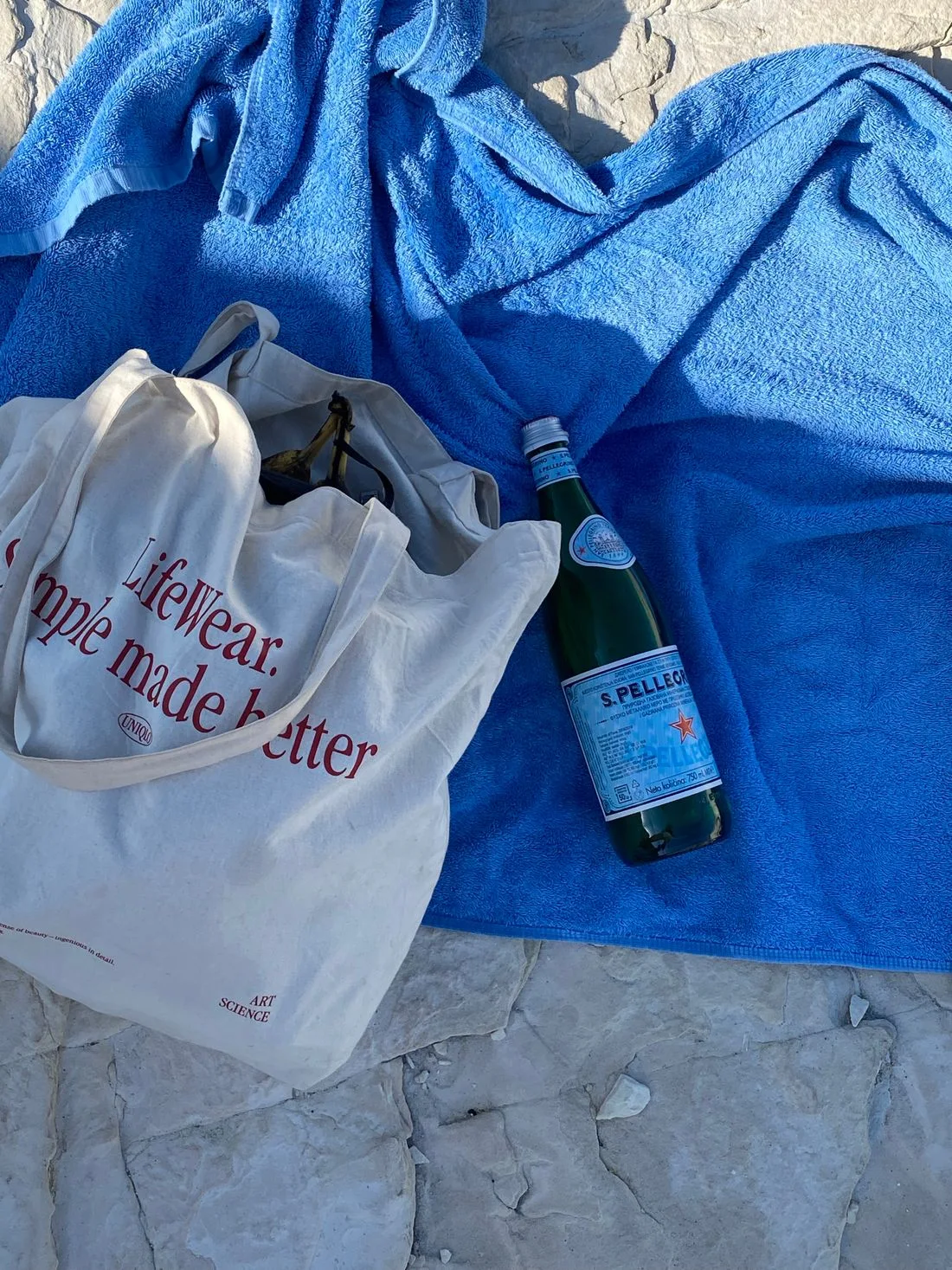 Tote bag and bottled water on a blue beach towel