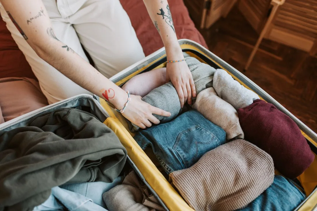Person packing clothing into an open suitcase