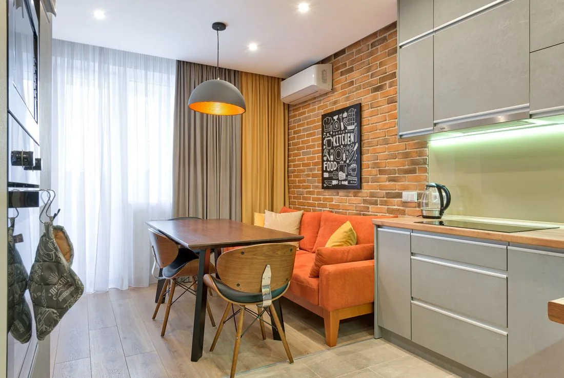 Compact apartment kitchen with a brick wall and dining area